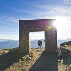 Zwei Wanderer hinter einem steinernen Tor in den Bergen