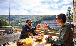 Zwei Biker auf der Terrasse einer Hütte bei der Jause.